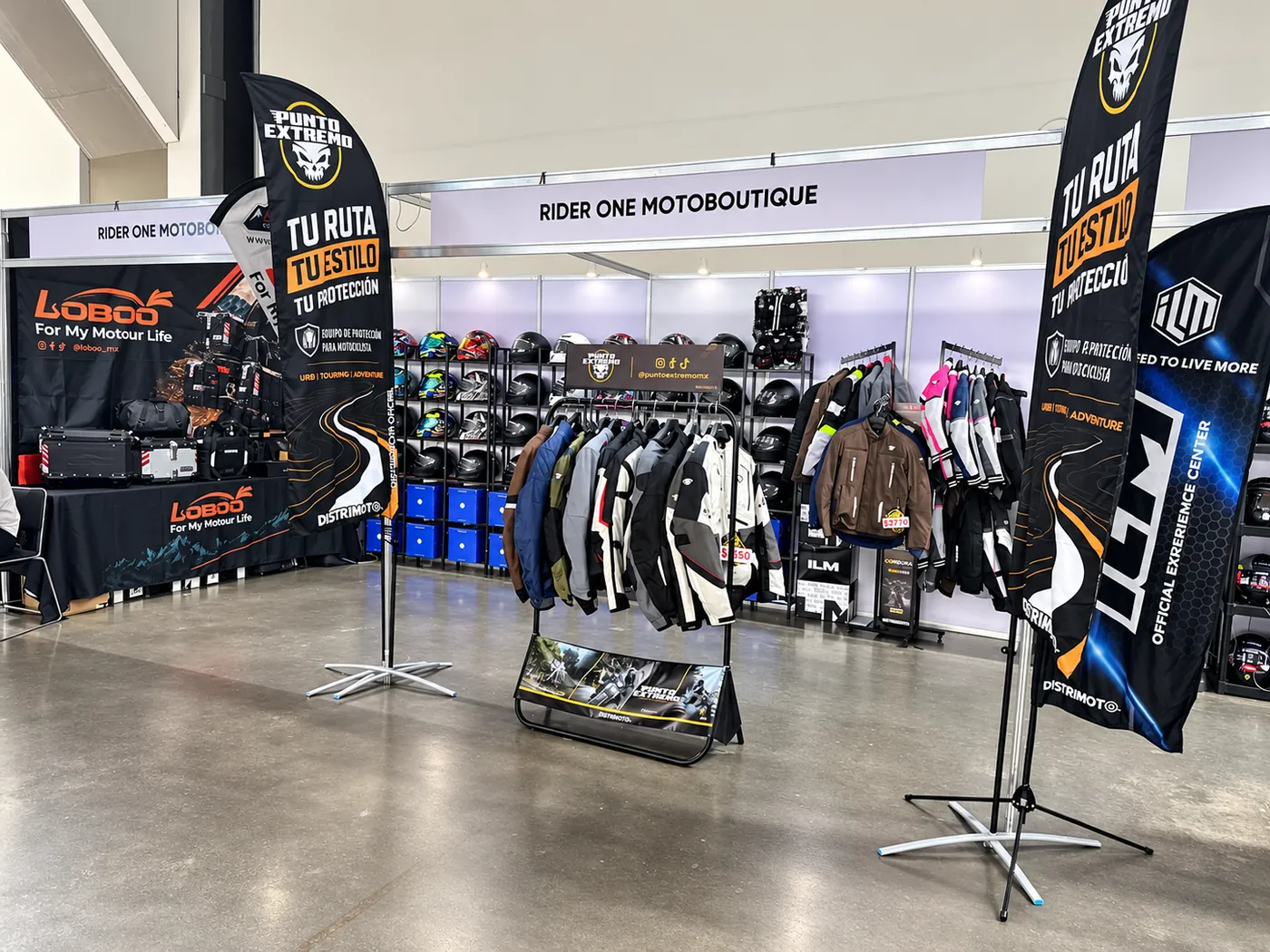 Stand de Distrimoto con chamarras, cascos y banderolas de Punto Extremo, ILM y LOBOO en FICMOTO 2026