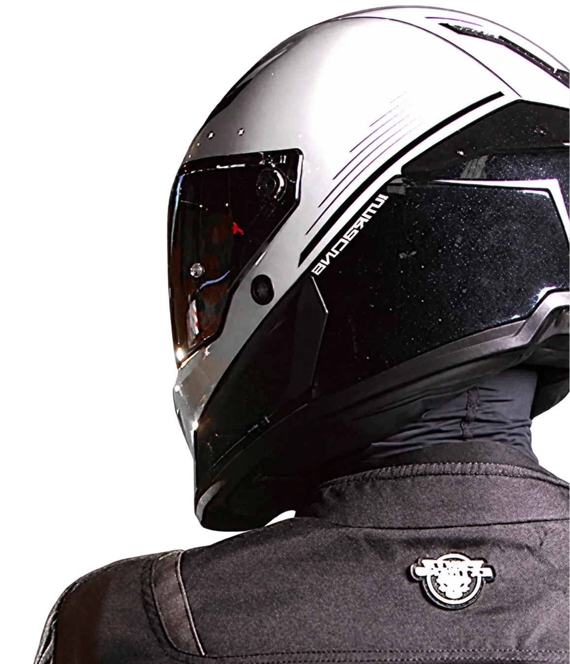 Motorista con casco blanco y negro y chaqueta oscura, visto de perfil desde atrás